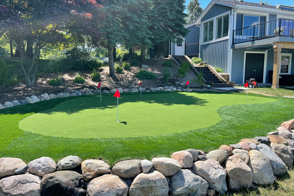 Putting green with red flags. Area is surrounded by rocks.