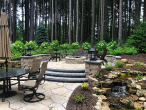 Small waterfall near outdoor lounging area and patio with firepit