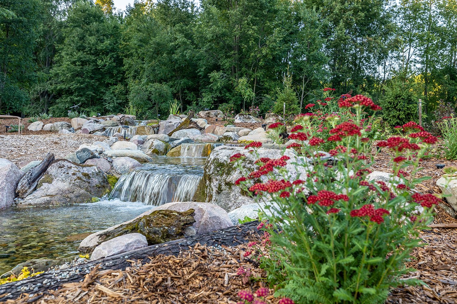 Multi-layer waterfall surrounded by plants and trees.